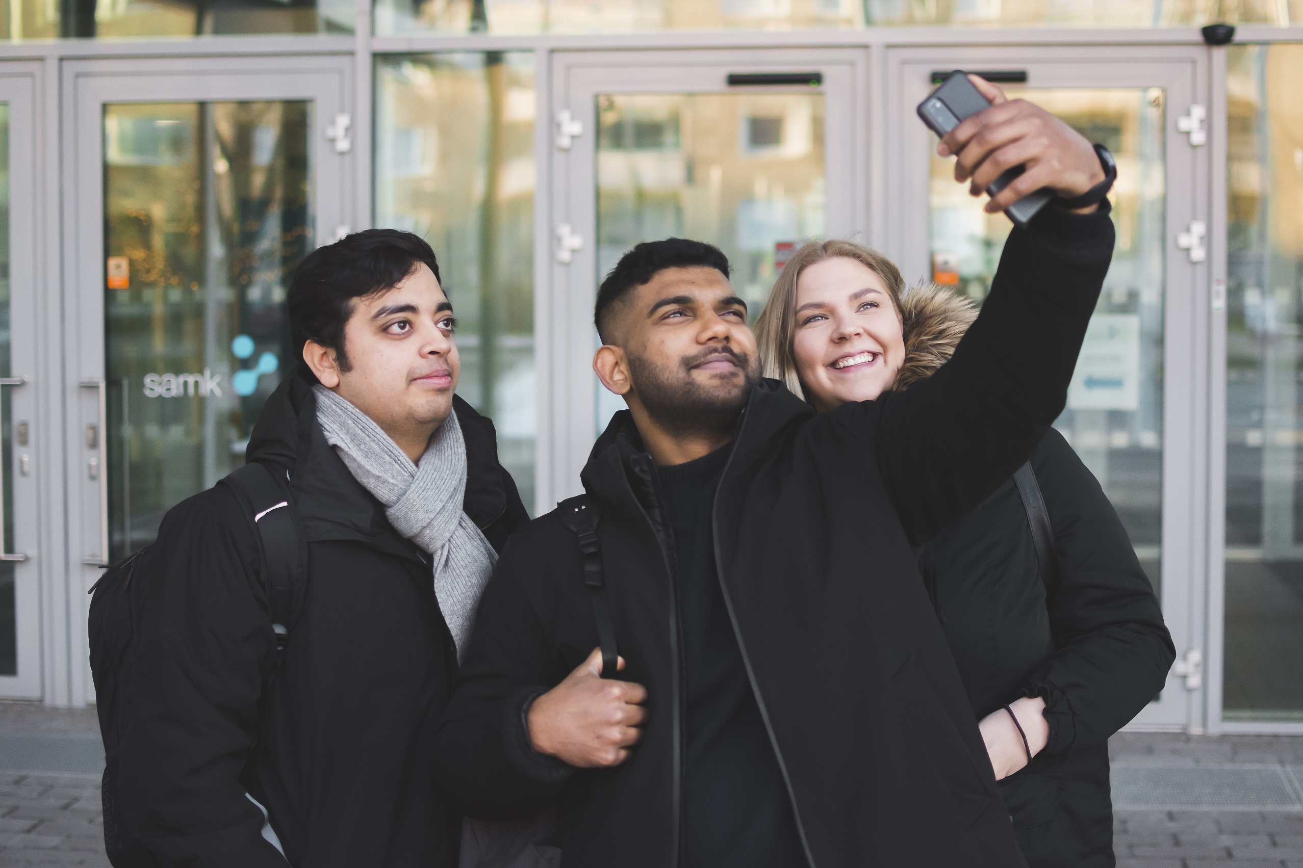 Kolme opiskelijaa ottamassa selfietä