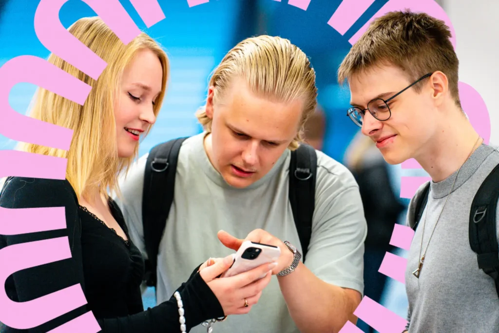 Kolme opiskelijaa katsomassa yhdessä Tuudoa