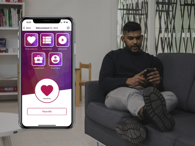 Kännykän ruudulla näkyy Tuudon Rekrymessut 2022 -näkymä. Mies katsoo puhelinta.