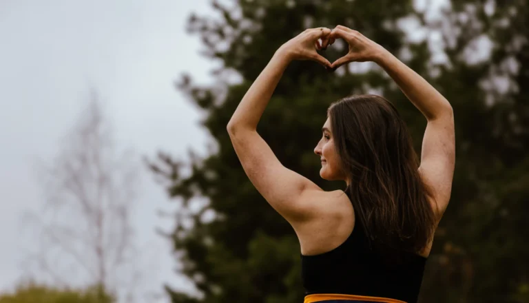 Opiskelija selkä kameraan näyttää sydän-merkkiä.